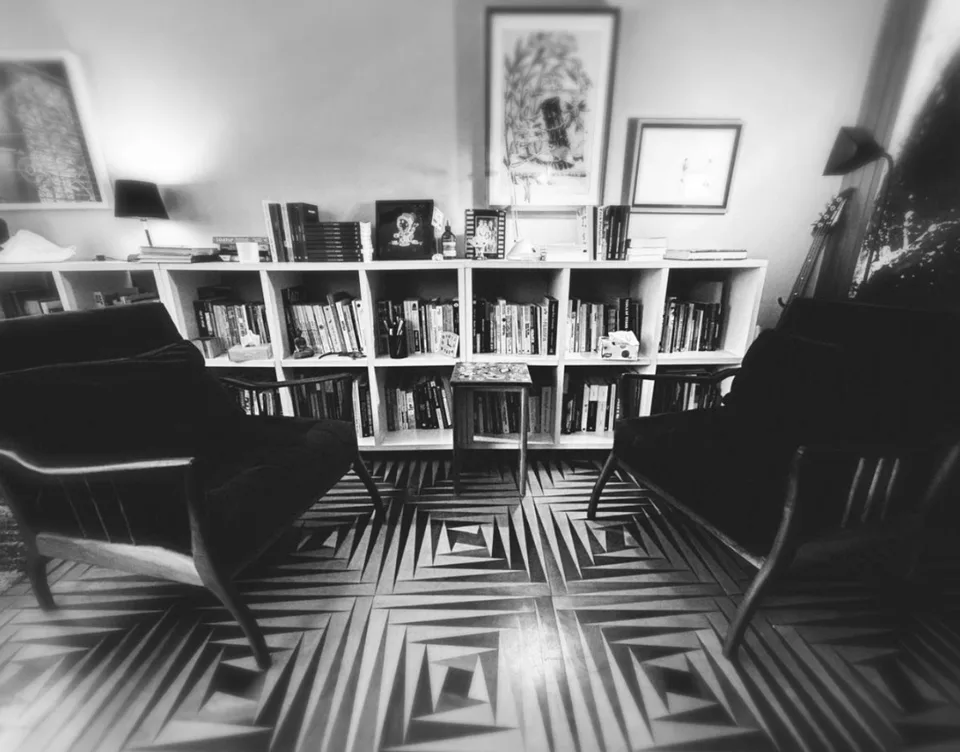 O estúdio do autor: estante de livros e duas poltronas